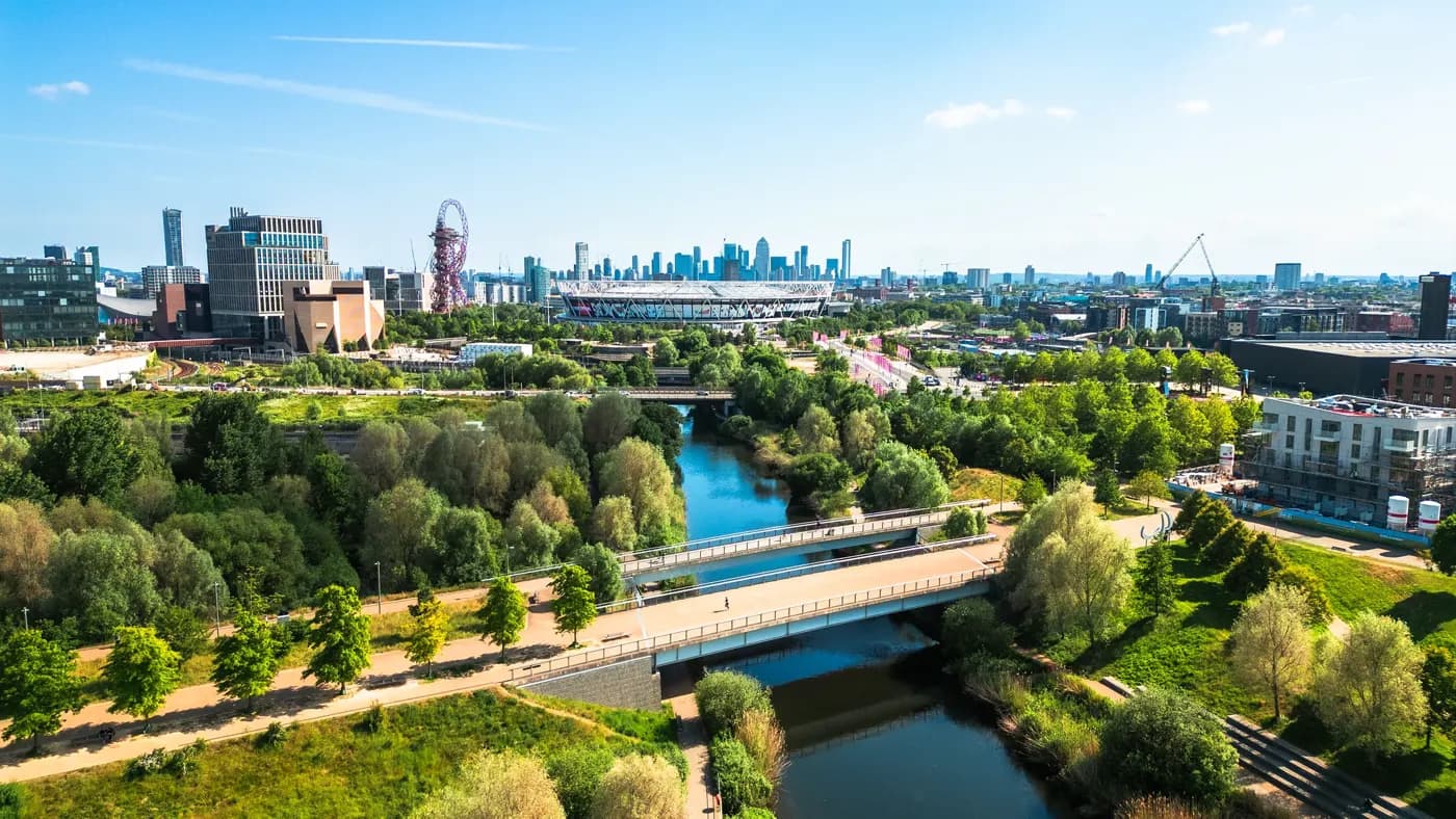 Aerial view, taken by drone, depicting the modern architecture of Stratford in East London. In the foreground is Stratford wetlands on the River Lea, while the skyline is dominated by Queen Elizabeth Olympic Park and London Stadium, home of West Ham United FC. The high rise towers of the Isle of Dogs, including Canary Wharf, are visible on the horizon.