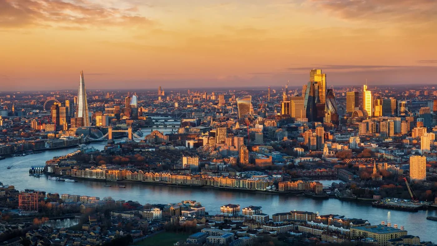 Panoramic, elevated view of the urban London skyline with soft, golden sunlight during sunrise, England