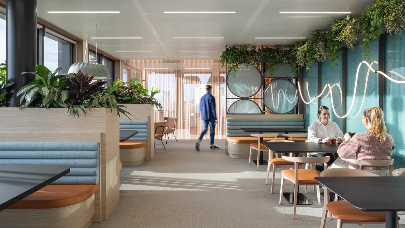 A group of people in a modern office furnished with plants and colourful furniture
