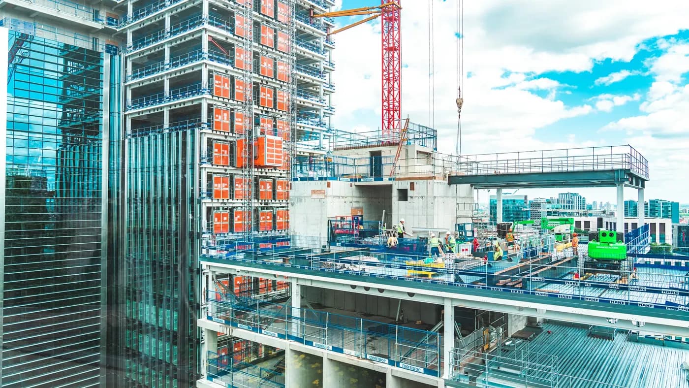 View at construction site with unfinished residential buildings against blue sky, London